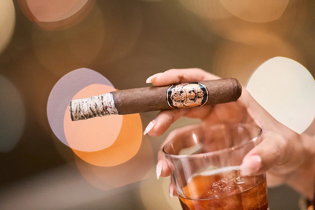 A Rose Gold Reserve cigar held beside a glass of wine