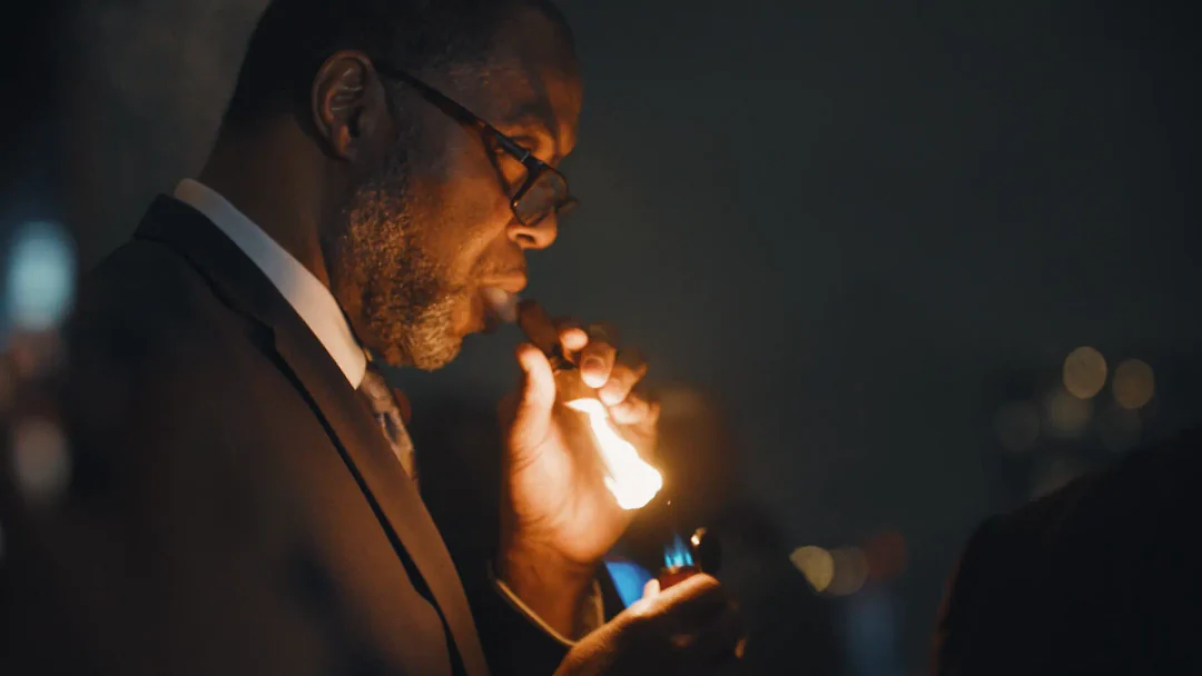 A guest lighting a Rose Gold Reserve cigar in a dark lounge